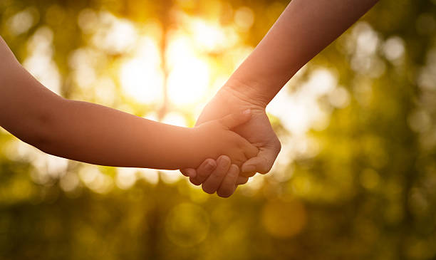 Close up of mother or older sister and a child hands at the sunset Close up of mother or older sister and a child hands at the sunset